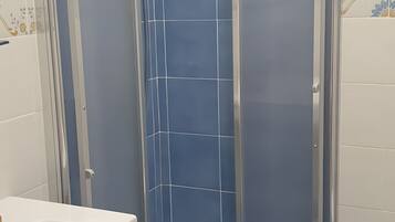 Un bagno con cabina doccia, lavandino e pareti piastrellate di blu.