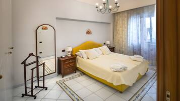 A hotel room with a large bed, a chandelier, a mirror, and a decorative ceiling.