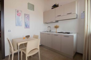 A compact kitchen with a dining area, featuring a sink, stove, cabinets, and a chair. - Apartment in Mazzarino with 1 bedrooms sleeps 2 (Mazzarino)