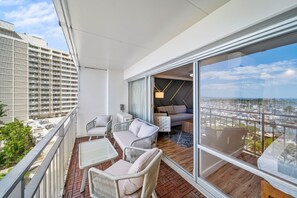 A balcony with wicker furniture, a sofa, and a view of a marina. - Renovated Ocean View 1 Bedroom Apartment @ The Ilikai Waikiki Beach, Honolulu (Honolulu)