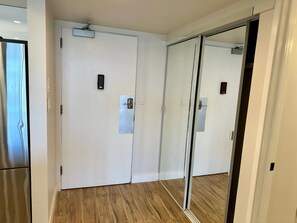 Una habitación con puerta corrediza de vidrio, una puerta blanca con cerradura y suelo de madera.