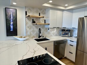 A modern kitchen with a marble countertop, stainless steel appliances, and a geometric backsplash. - Renovated Ocean View 1 Bedroom Apartment @ The Ilikai Waikiki Beach, Honolulu (Honolulu)