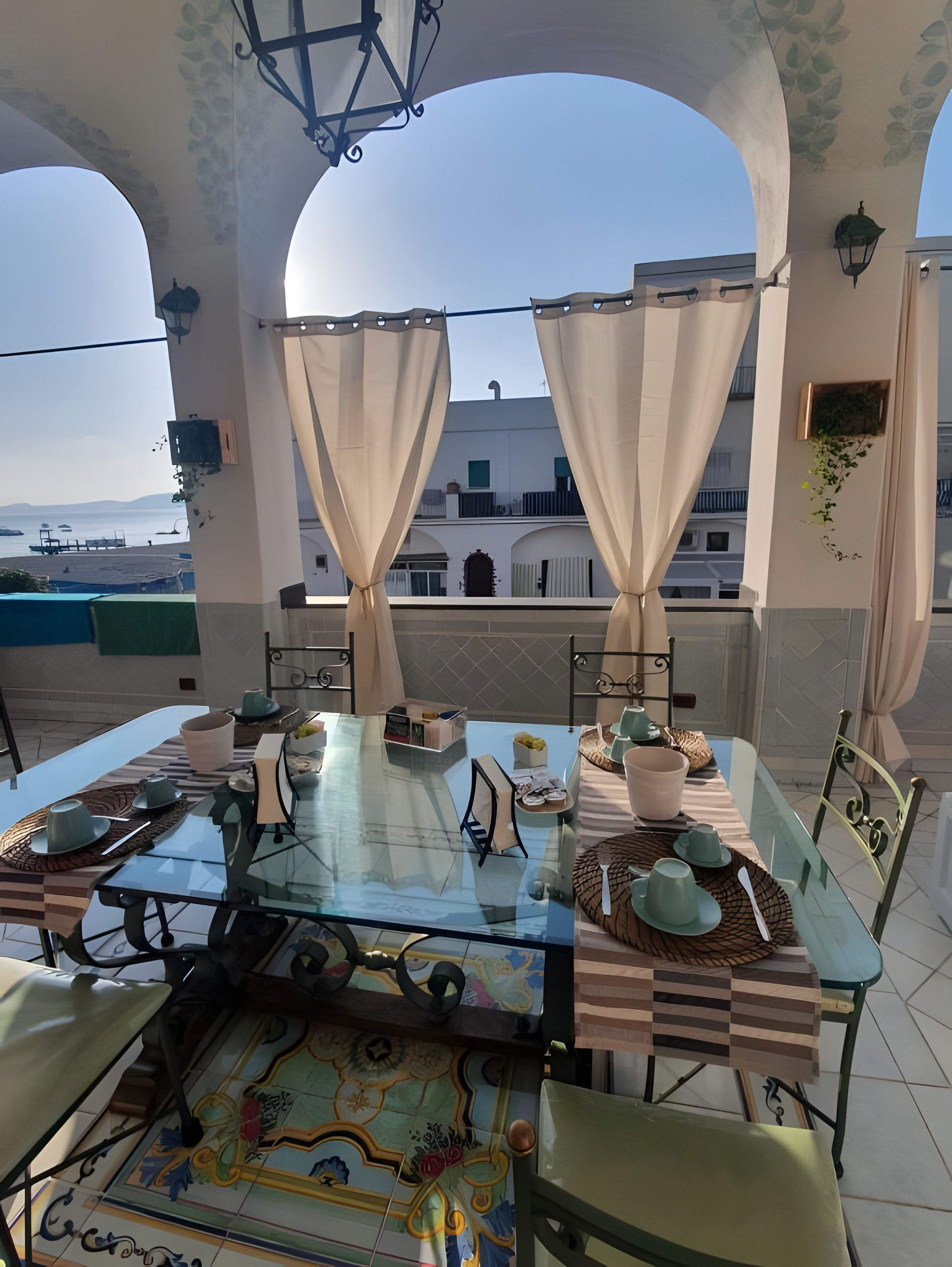 Un comedor con mesa de vidrio, sillas y vista al mar.