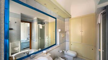 A bathroom with a large mirror, two sinks, a toilet, and a shower.