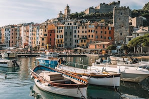 Un porto turistico con barche ormeggiate, un edificio storico con un campanile e colorati edifici lungo il lungomare.