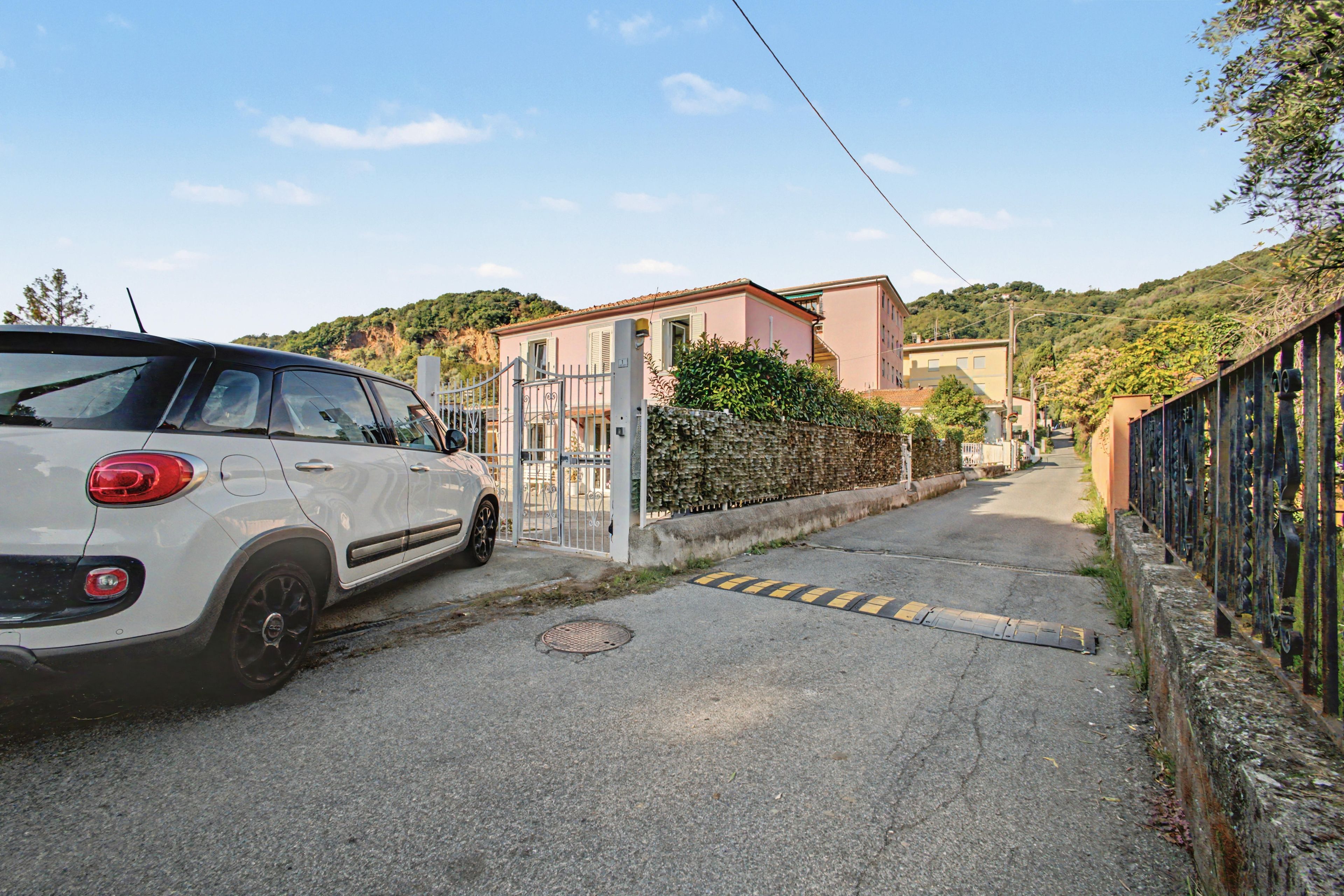Una stretta via con un'auto parcheggiata e un cancello che dà accesso a un edificio.