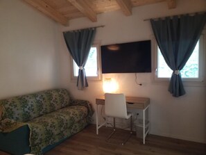 A room with a wooden ceiling, a sofa, a desk with a chair, and a television mounted on the wall. - Holiday Home 'Casa Di Lidia' with Shared Pool, Wi-Fi and Air Conditioning (Romito Magra)
