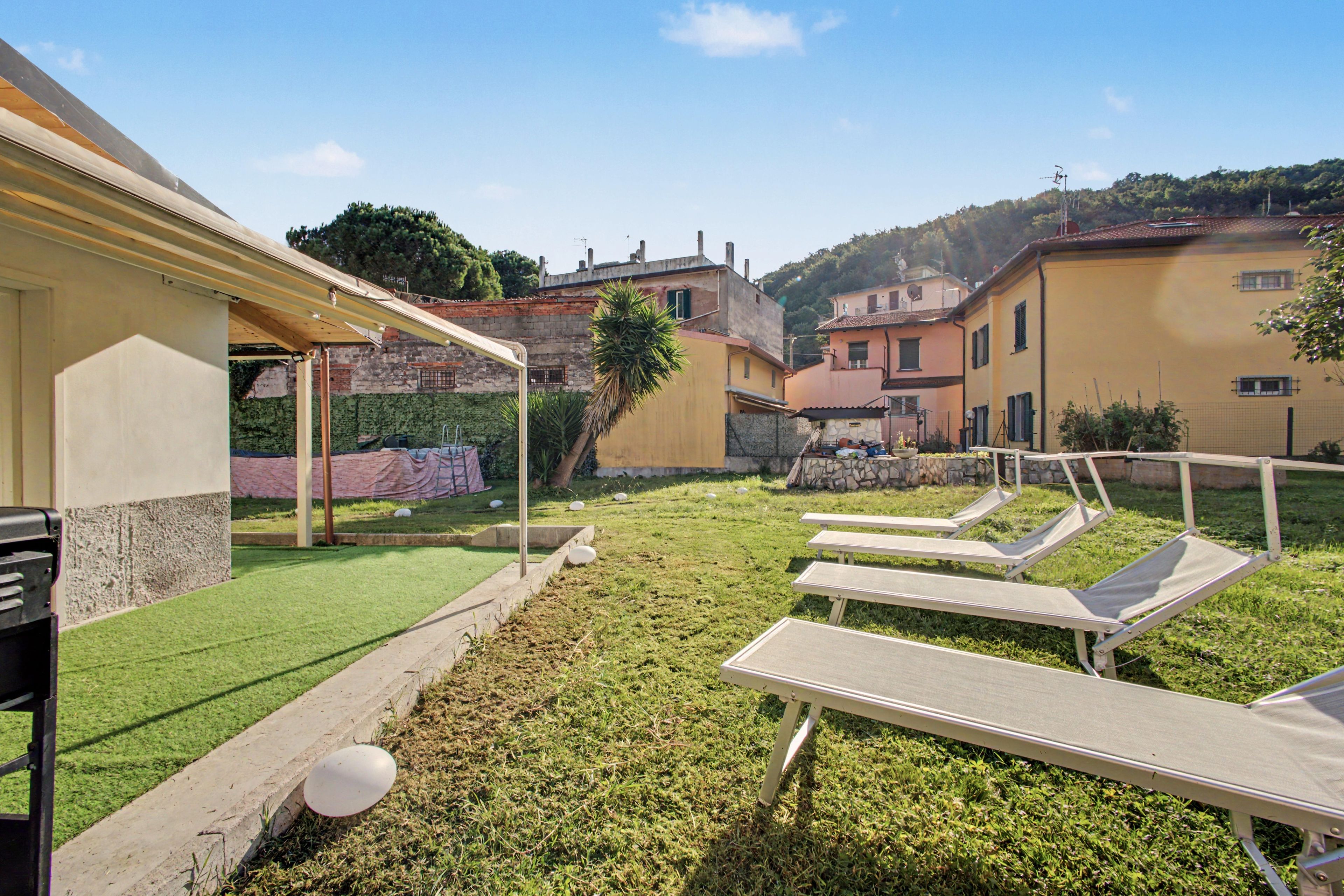 Un cortile con prato verde, una pergola e poltrone da relax.