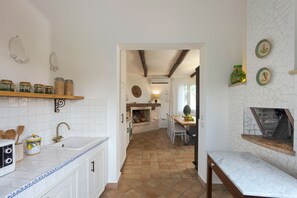 A kitchen with white cabinets, a sink, and a dining area with a table and chairs. - Stunning villa with private pool in Graniti, near Taormina – DiCasaInSicilia (Graniti)