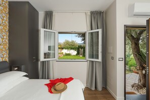 A bedroom with a bed, a window with curtains, a wardrobe, and a view of a garden. - Stunning villa with private pool in Graniti, near Taormina – DiCasaInSicilia (Graniti)