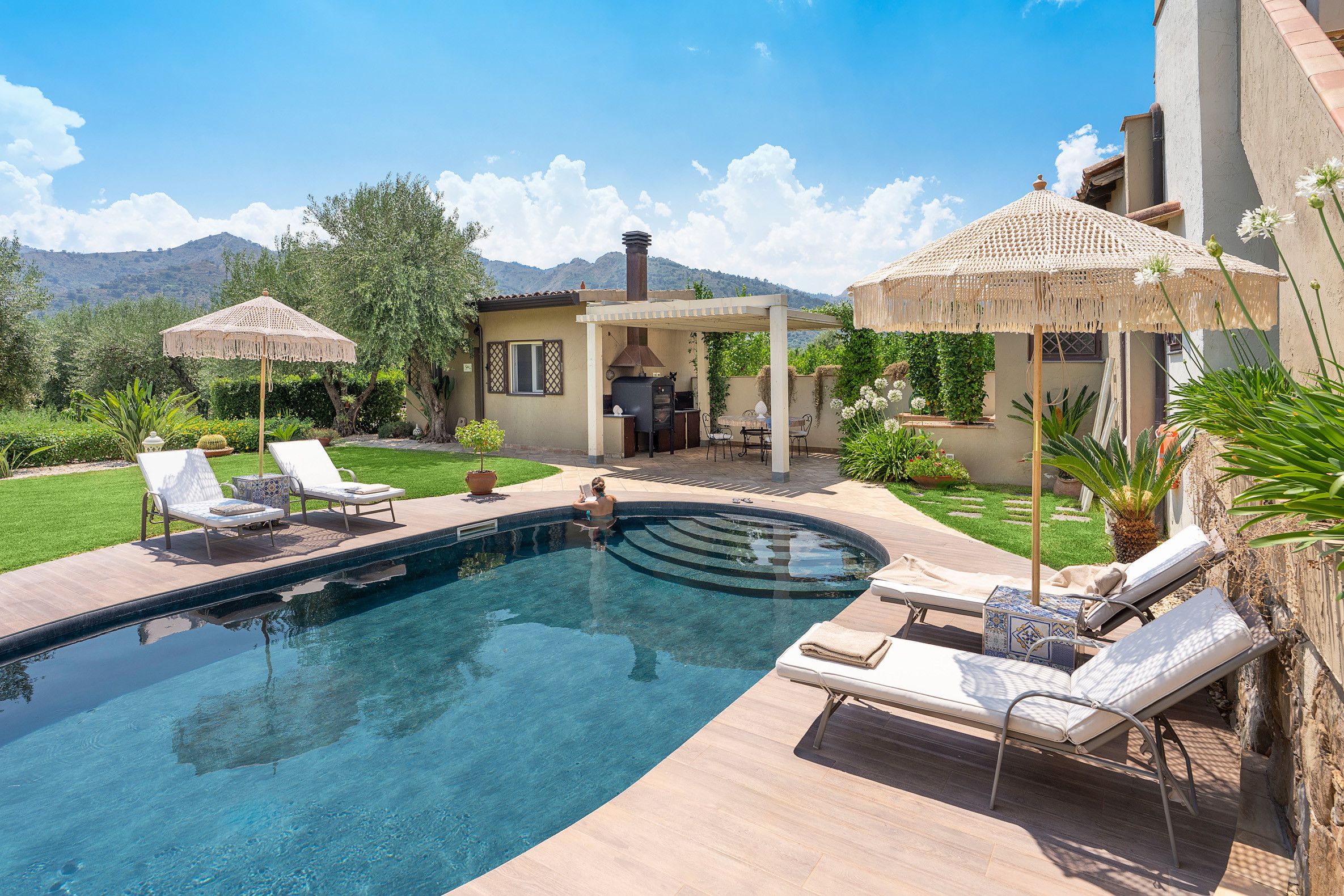 Una piscina con sillas de descanso, una pérgola y una zona de barbacoa.
