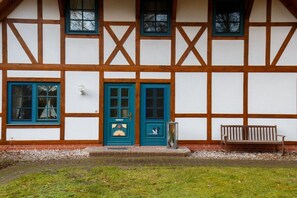 A traditional half-timbered building with a green door and blue windows. - House by the forest "Rümdriewer" (Born a. Darß)