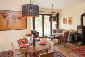 A dining area with a round table set for four, a large world map on the wall, and a cozy living area with a sofa and a fireplace. - Vrbo Property (Lenz)