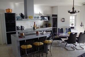 Une cuisine moderne dotée d’un îlot central, de tabourets de bar et d’une table à manger avec des chaises.