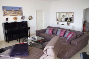 Un salon comprenant un canapé, une table basse, un téléviseur et des objets décoratifs accrochés au mur.