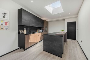 A modern kitchen with a skylight, dark cabinetry, and a wooden countertop. - Elysium Beachfront Apartment | Sea Views & Parking (Barry)