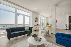 Ein großzügiger Wohnbereich mit großem Fenster, einer Couch, einem Couchtisch und einem Essbereich mit Stühlen.
