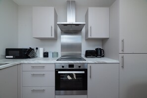 A modern kitchen with a built-in oven, microwave, and coffee maker. - Sovereign Quay 1BR Apartment | Old Town Hull (Kingston upon Hull)