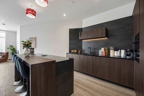 Een moderne keuken met donkerhouten kastjes, een centraal eiland en een ingebouwde oven.
