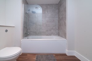 A bathroom with a shower, toilet, and a rug on the floor. - 1-Bedroom Stay | Hull Old Town & Museums Quarter (Kingston upon Hull)