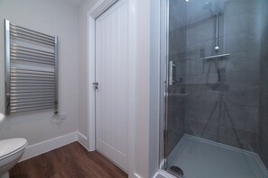 A bathroom with a toilet, a glass-enclosed shower, and a towel rack. - Chic Old Town Apartment | Free Parking (Kingston upon Hull)