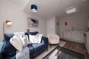 A modern living room with a sofa, a coffee table, a lamp, and a painting on the wall. - Chic Old Town Apartment | Free Parking (Kingston upon Hull)