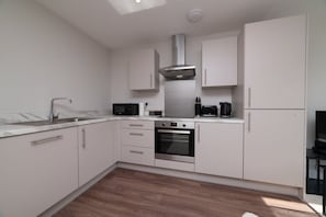 Een moderne keuken met witte kasten, een roestvrijstalen afzuigkap, een magnetron en een oven.