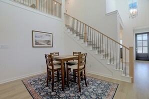A dining area with a table and chairs, a patterned rug, a staircase with a railing, and a framed picture on the wall. - 7 Mi to Dtwn Rosenberg: Spacious Family Home (Rosenberg)