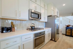 A modern kitchen with white cabinetry, stainless steel appliances, and a tiled backsplash. - 7 Mi to Dtwn Rosenberg: Spacious Family Home (Rosenberg)
