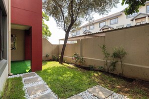 Un'area residenziale con un vialetto lastricato, un piccolo prato e un albero.