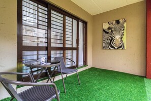 Una stanza con una porta in vetro, due sedie, un tavolino e un quadro raffigurante una zebra sulla parete.