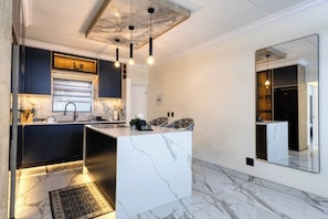 A modern kitchen with marble countertops, pendant lighting, and a built-in island. - Elegant 2-Bedroom Retreat in Fourways, Johannesburg (Sandton)
