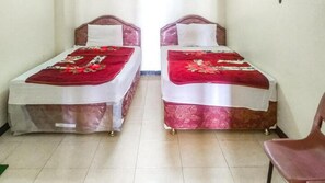 Une chambre avec deux lits simples, chacun étant recouvert d’une courtepointe rouge et blanche et agrémenté d’un oreiller blanc.