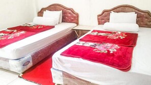 Deux lits simples avec des têtes de lit en bois et des couvre-lits à motifs floraux rouges.