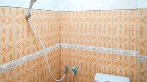 Une salle de bain avec des carreaux décorés, un flexible de douche et des toilettes.