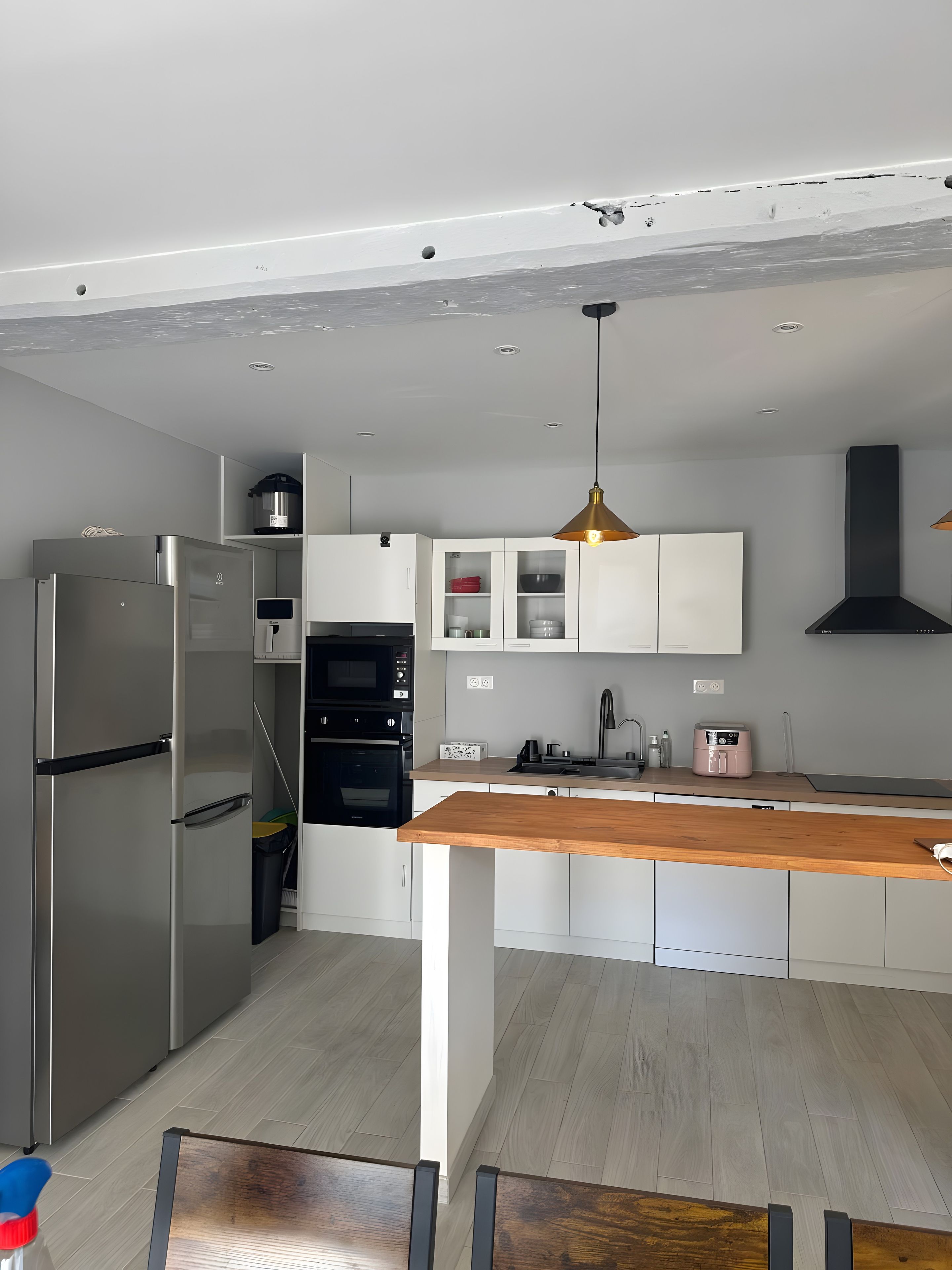 Una cucina moderna con elettrodomestici in acciaio inossidabile, mobili bianchi e un piano di lavoro in legno.
