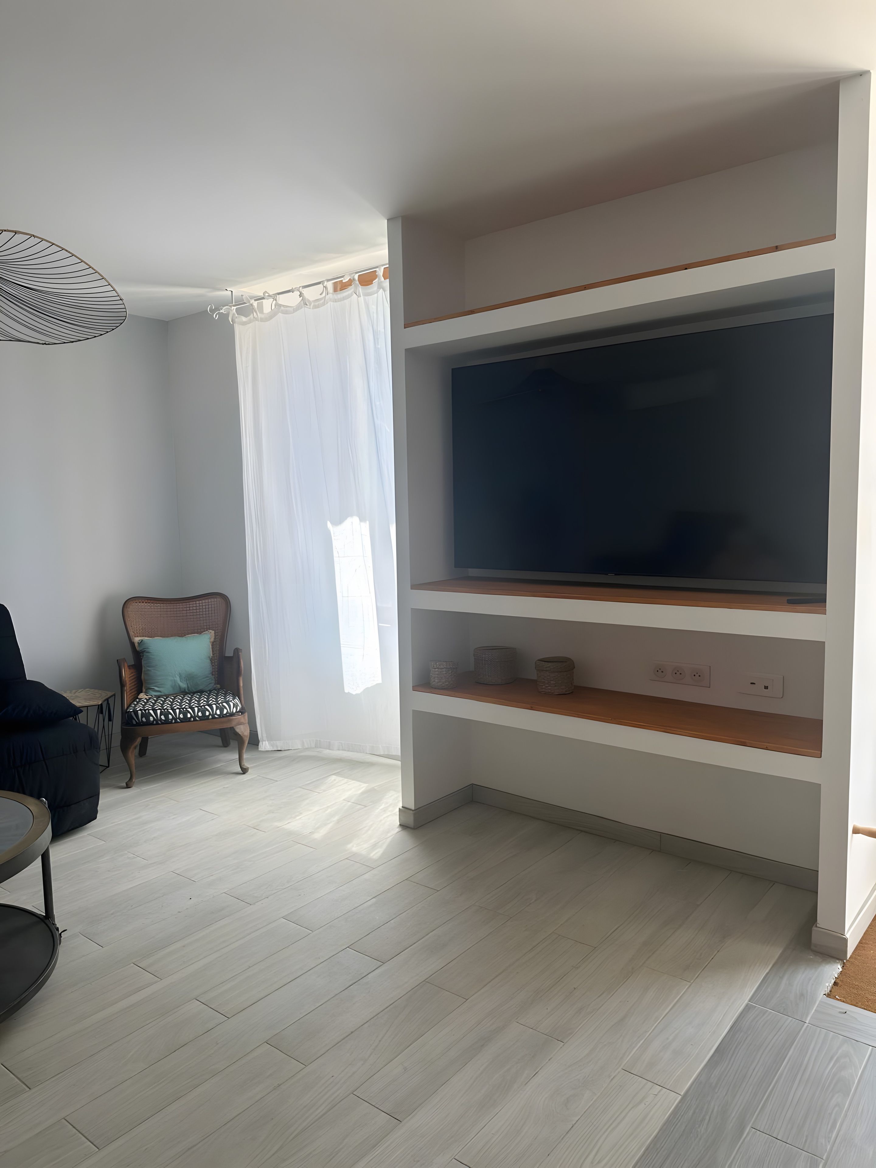 A living room with a TV, a chair, and a small table.
