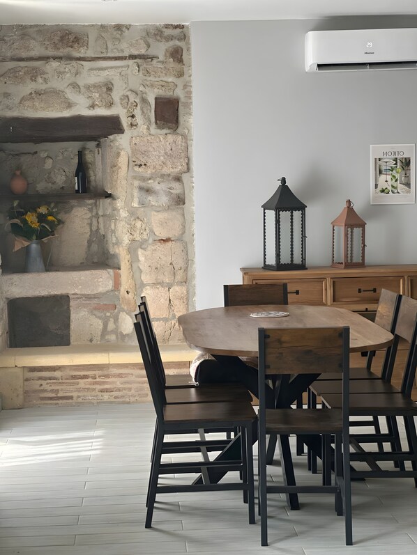 Comedor con pared de piedra, mesa de madera y sillas.
