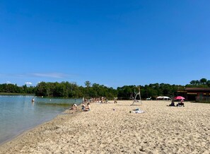 A sandy beach with a clear sky, a volleyball net, and a few people.