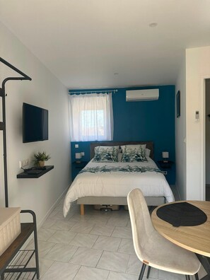 A bedroom with a bed, a TV, a desk, and a chair.