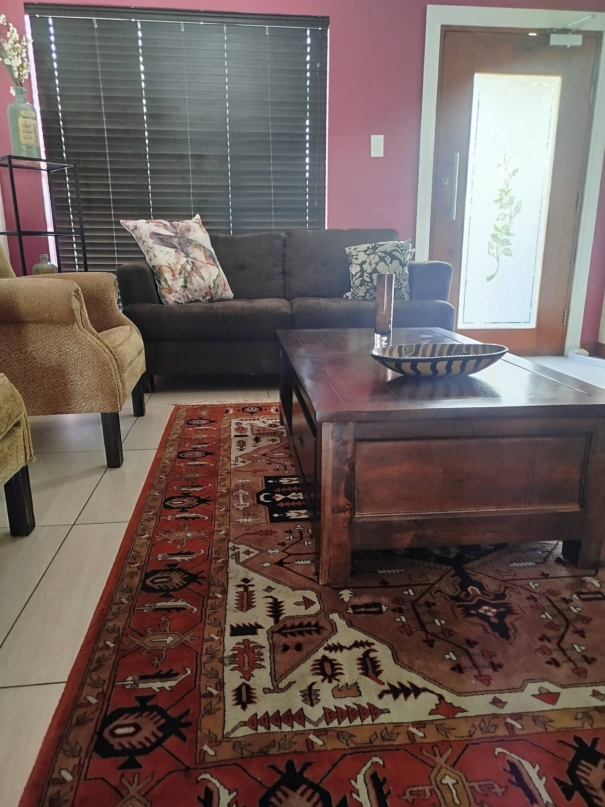 Een woonkamer met een bank, fauteuil, salontafel en een kamerkleed met dessin.