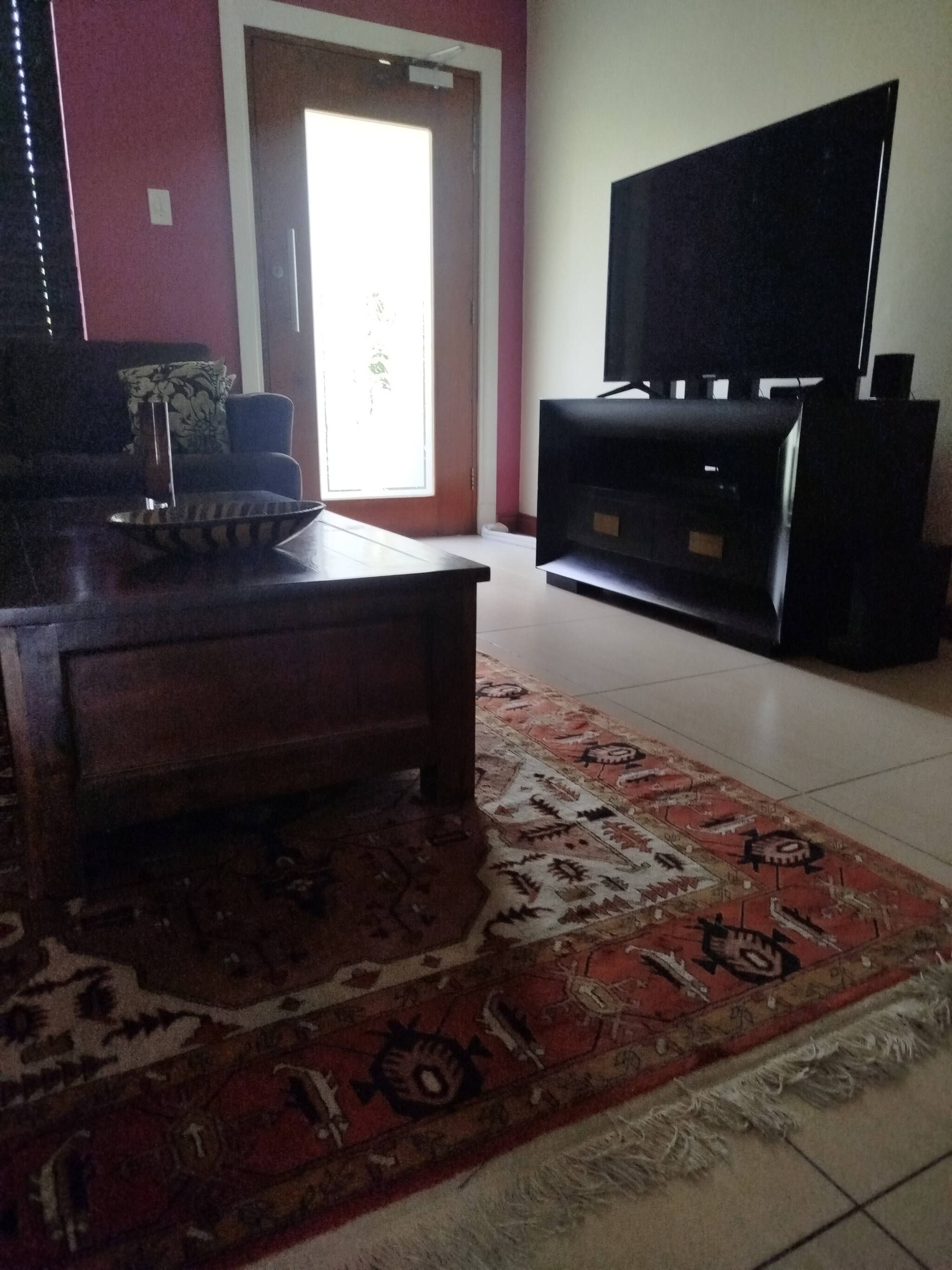 Una sala de estar con sofá, mesa de centro, televisor y altavoces.