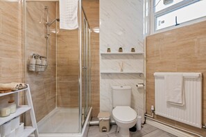 Een moderne badkamer met een douchecabine van glas, een toilet en een radiator.