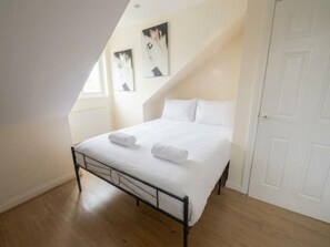 A bedroom with a bed, white bedding, a door, and a window. - St Peters Nest -Stylish 1-Bed Flat (Croydon)