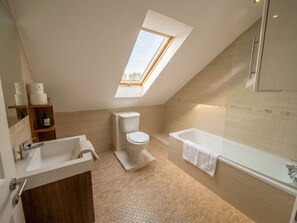Ein modernes Badezimmer mit Oberlicht, einer Badewanne und einer Toilette.