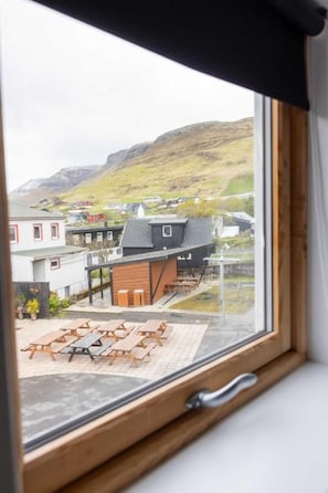 A window view of a building with a wooden deck and outdoor seating. - Lambastovubrekkan 6 (Sørvágur)
