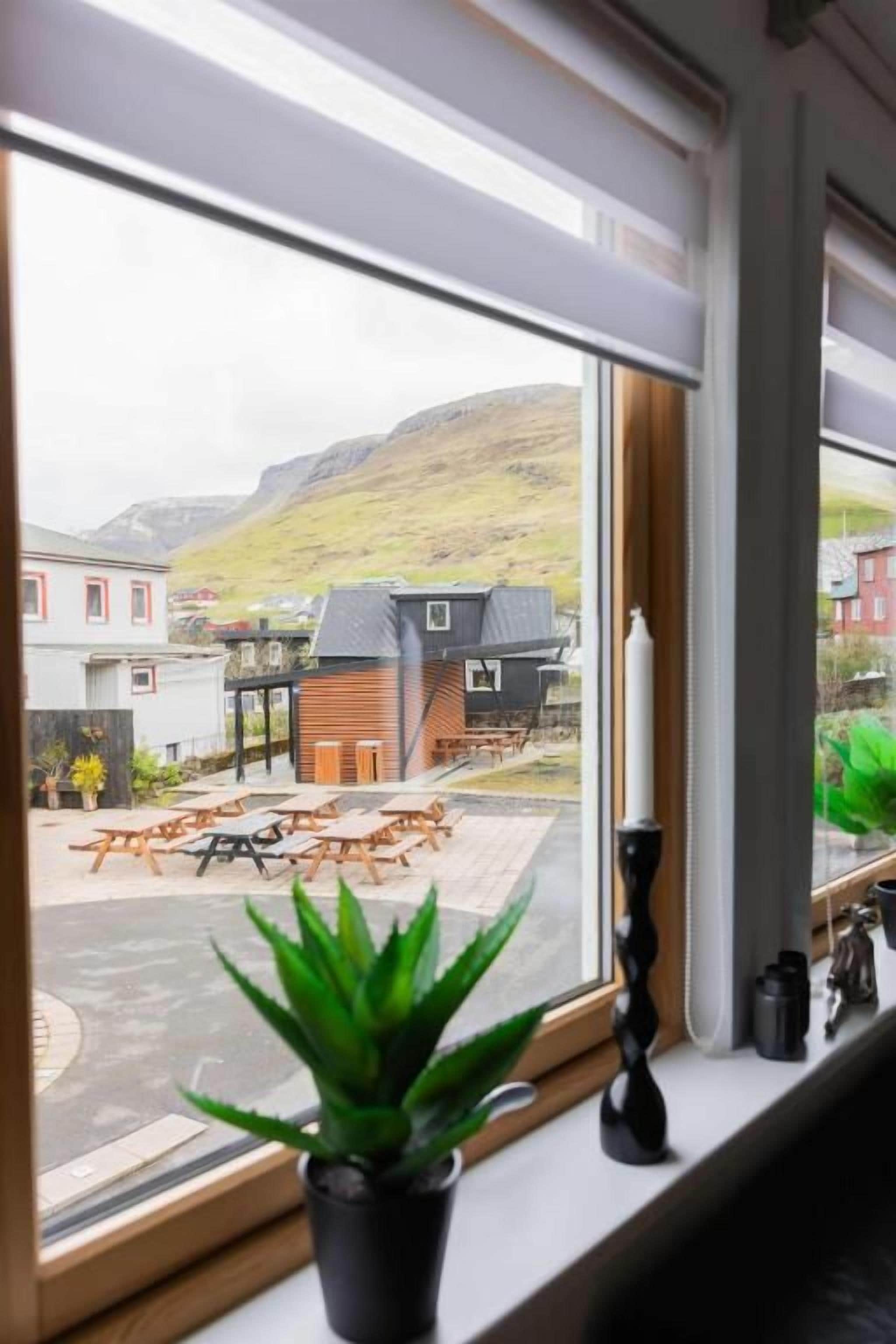 A window with a view of a building and a mountain.
