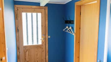 Una habitación con puerta de madera, pared azul y un perchero con ganchos.