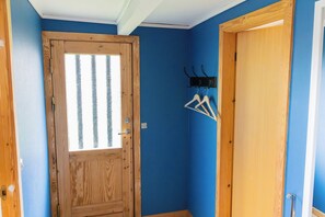 Une pièce avec une porte en bois, un mur bleu et un porte-manteau avec des cintres.
