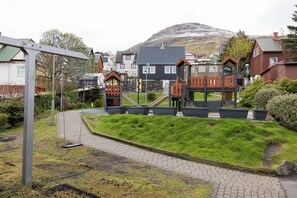 Un quartier résidentiel avec des maisons, une aire de jeux et un chemin pavé.